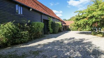 A gravel driveway leading to a building with a red-tiled roof and dark siding.