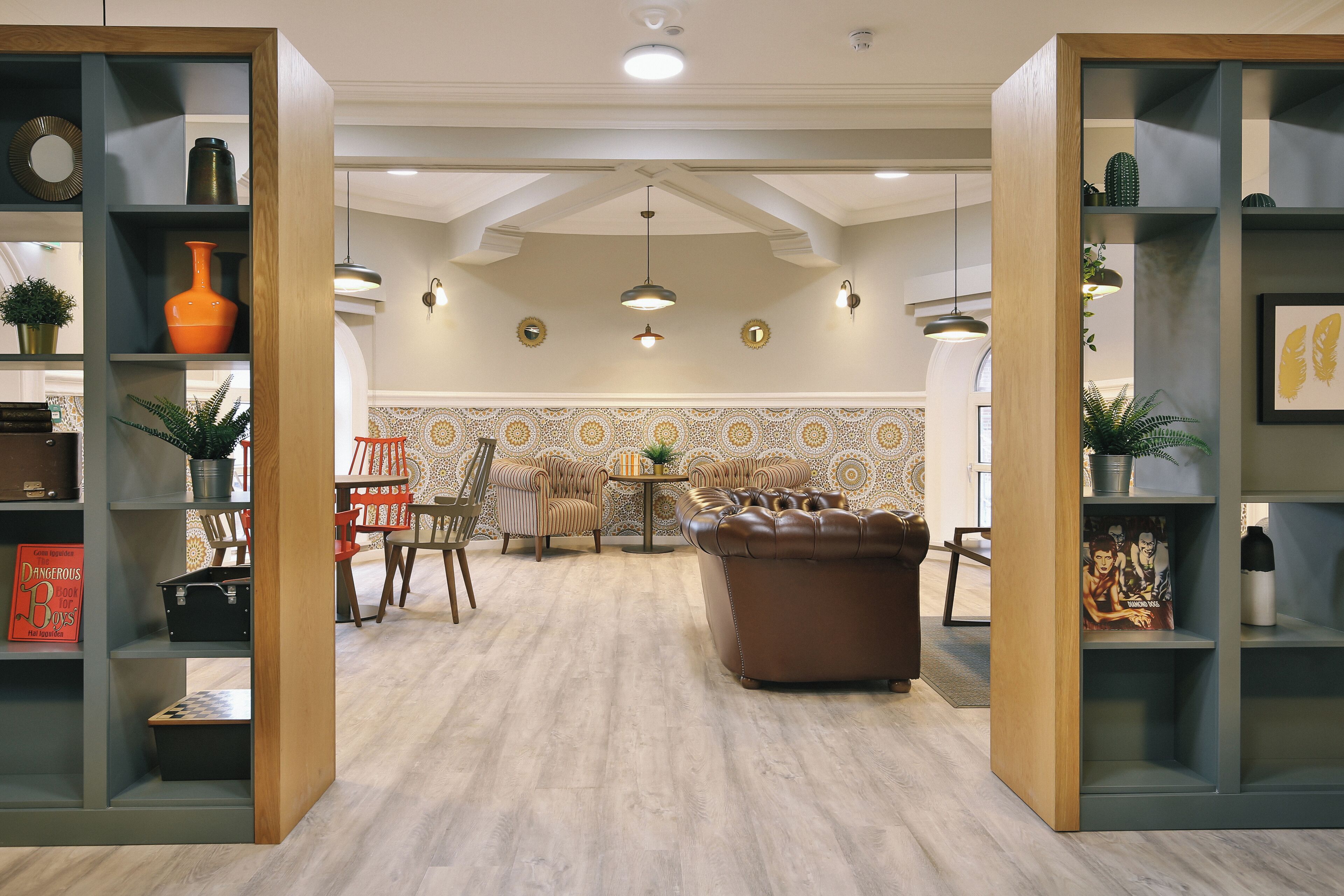Un salon moderne avec un canapé en cuir marron, des étagères en bois et un mur recouvert de carreaux décoratifs.