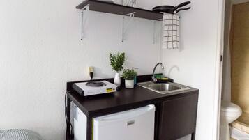 A compact kitchenette with a stove, sink, and a small refrigerator.