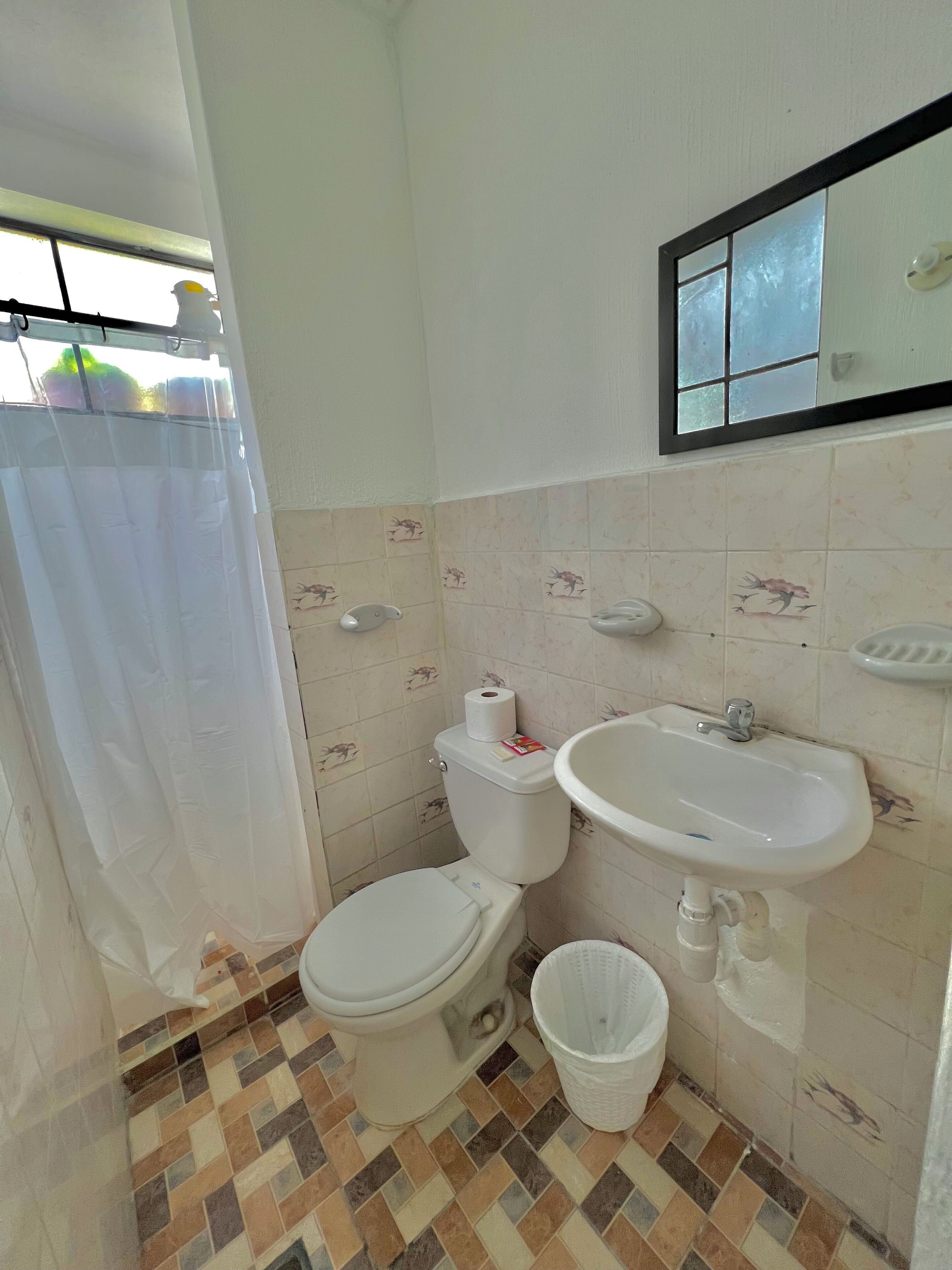 A small bathroom with a toilet, sink, and a shower curtain.