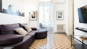 A modern living room with a leather sofa, a flat-screen TV, and a patterned rug.