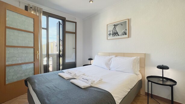 A hotel room with a bed, a nightstand, a framed picture on the wall, and a sliding glass door. - Stay U-nique Apartments Calabria (Barcelona)