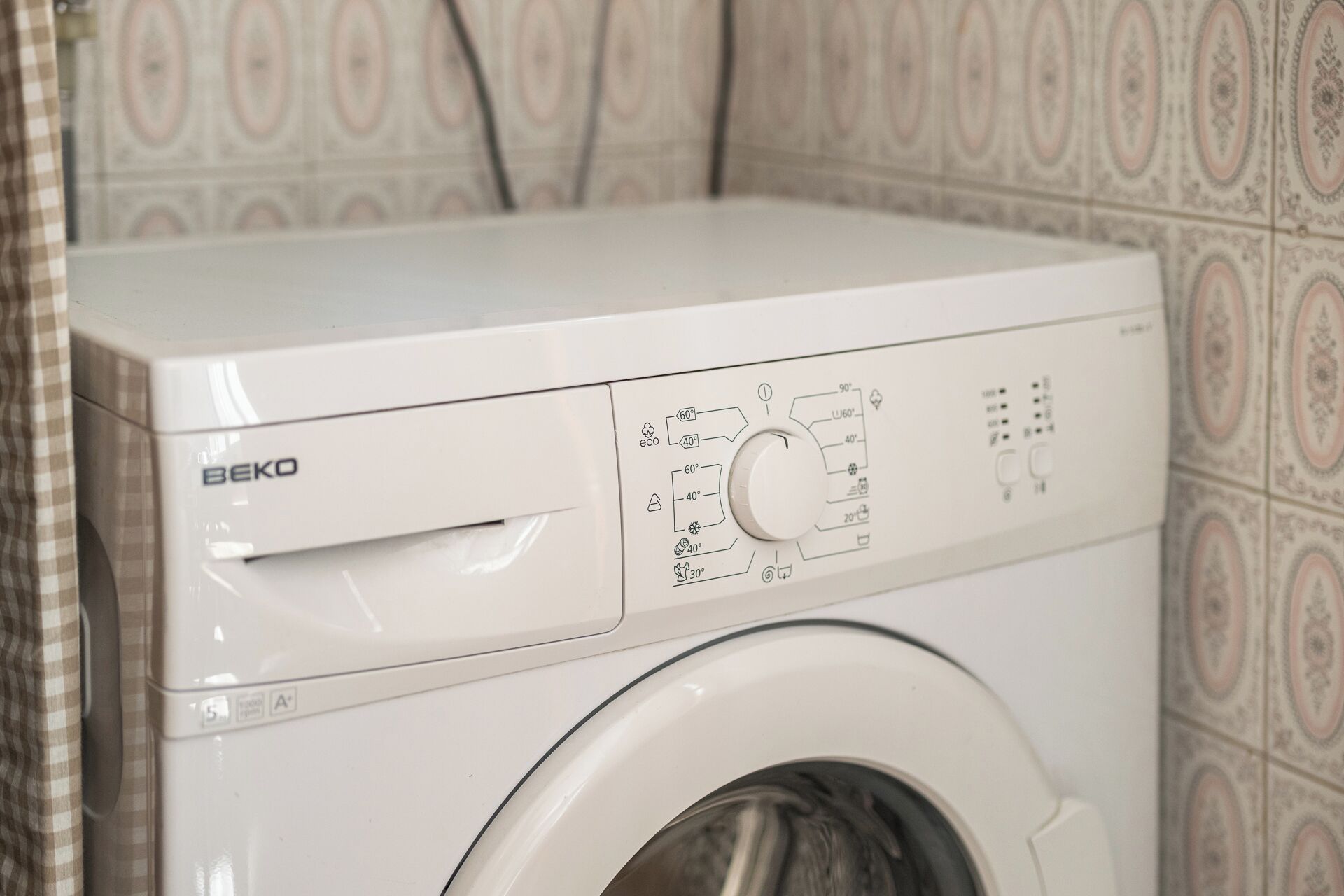 Vista frontal de una lavadora Beko blanca con panel de control que muestra ajustes de temperatura y un programa de secado suave.