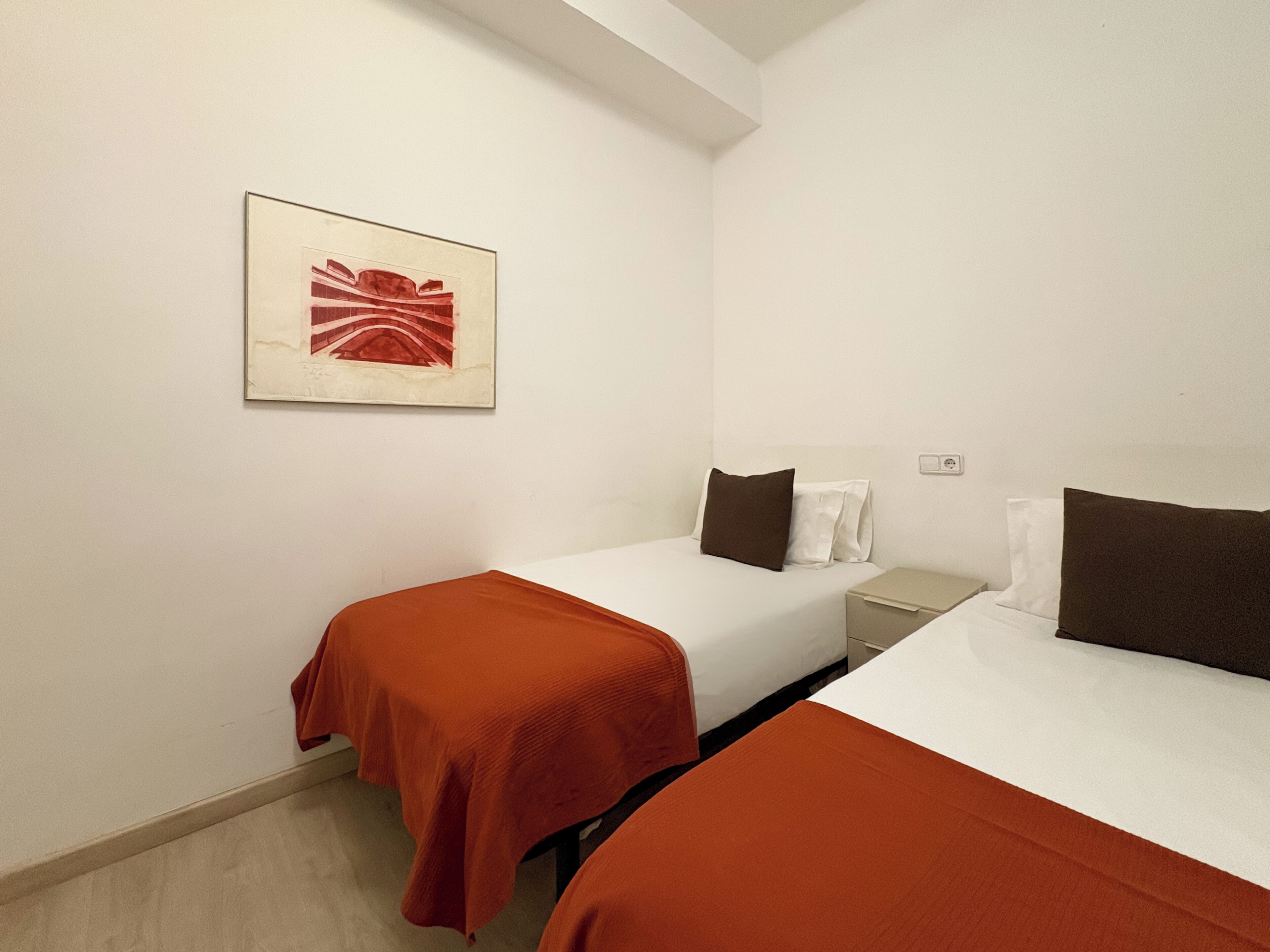 Una camera d'albergo con due letti, un comodino, una lampada e un quadro appeso al muro.