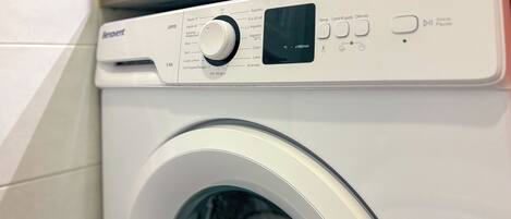 Vue de face d’un lave-linge à chargement frontal, avec un panneau de commande comprenant un sélecteur et des boutons pour différents réglages.