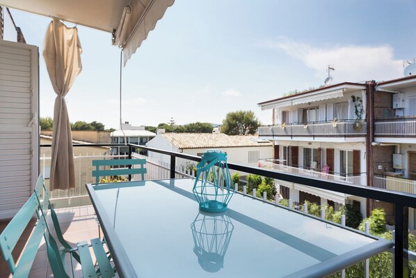 A balcony with a glass table, a teal lantern, and a view of neighboring buildings. - Stay U-nique Apartments Sitges Beach (Sitges)
