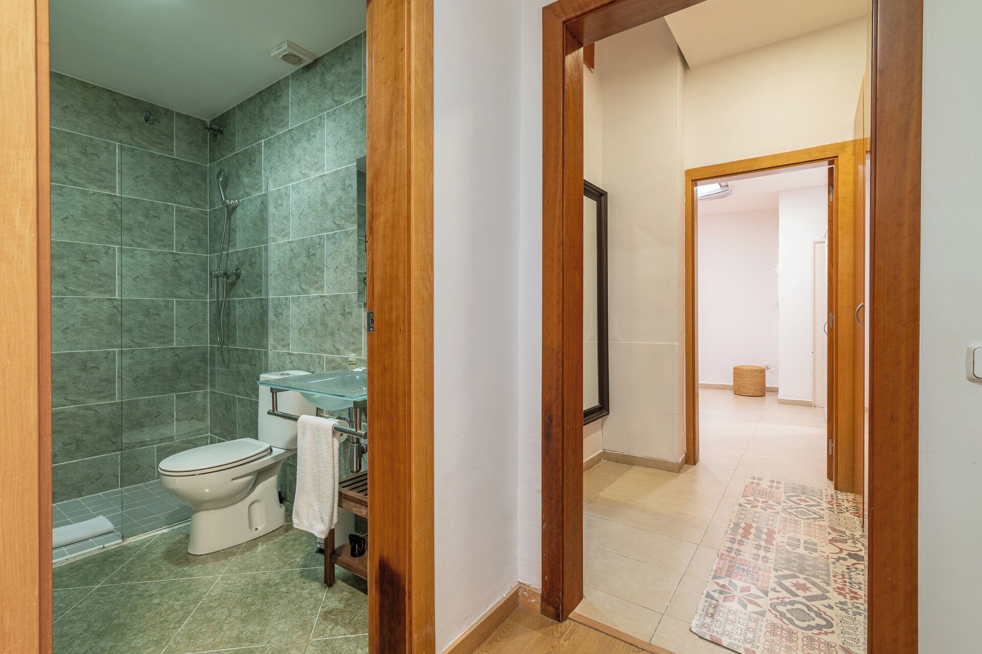 Un baño con lavamanos de vidrio, inodoro y ducha.