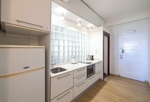 Eine moderne Küche mit Kühlschrank, Backofen, Spüle und einer weißen Arbeitsplatte.