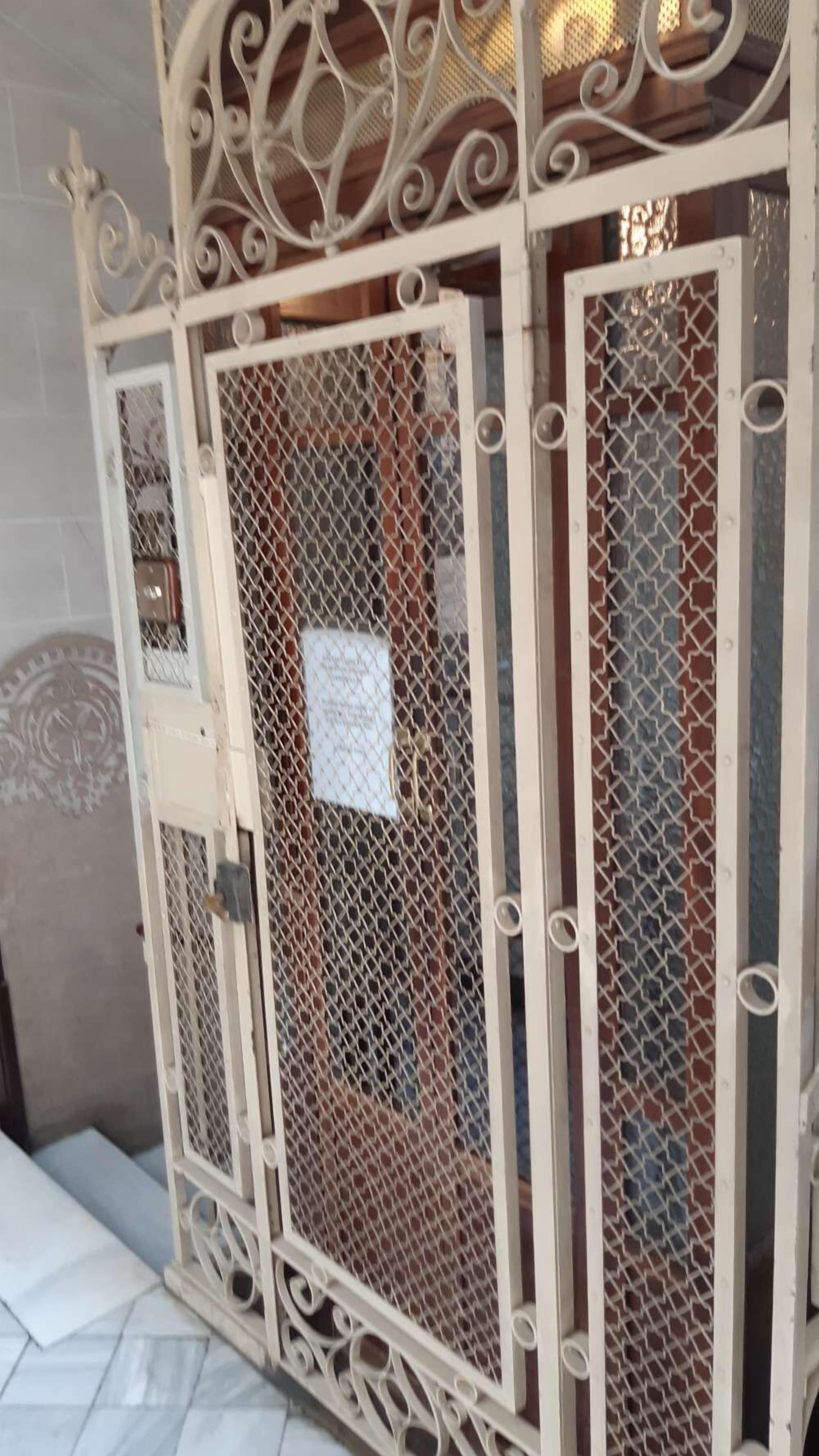 Una reja metálica blanca con diseños intrincados y un panel de malla.