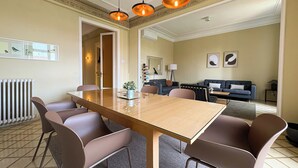 Une salle à manger moderne avec une grande table en bois, six chaises et trois lampes suspendues.