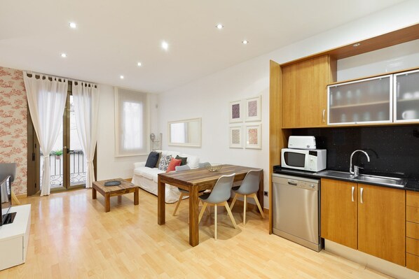 A compact living space with a dining area, kitchenette, and a sofa set. - Stay U-nique Apartments Terrassa (Barcelona)