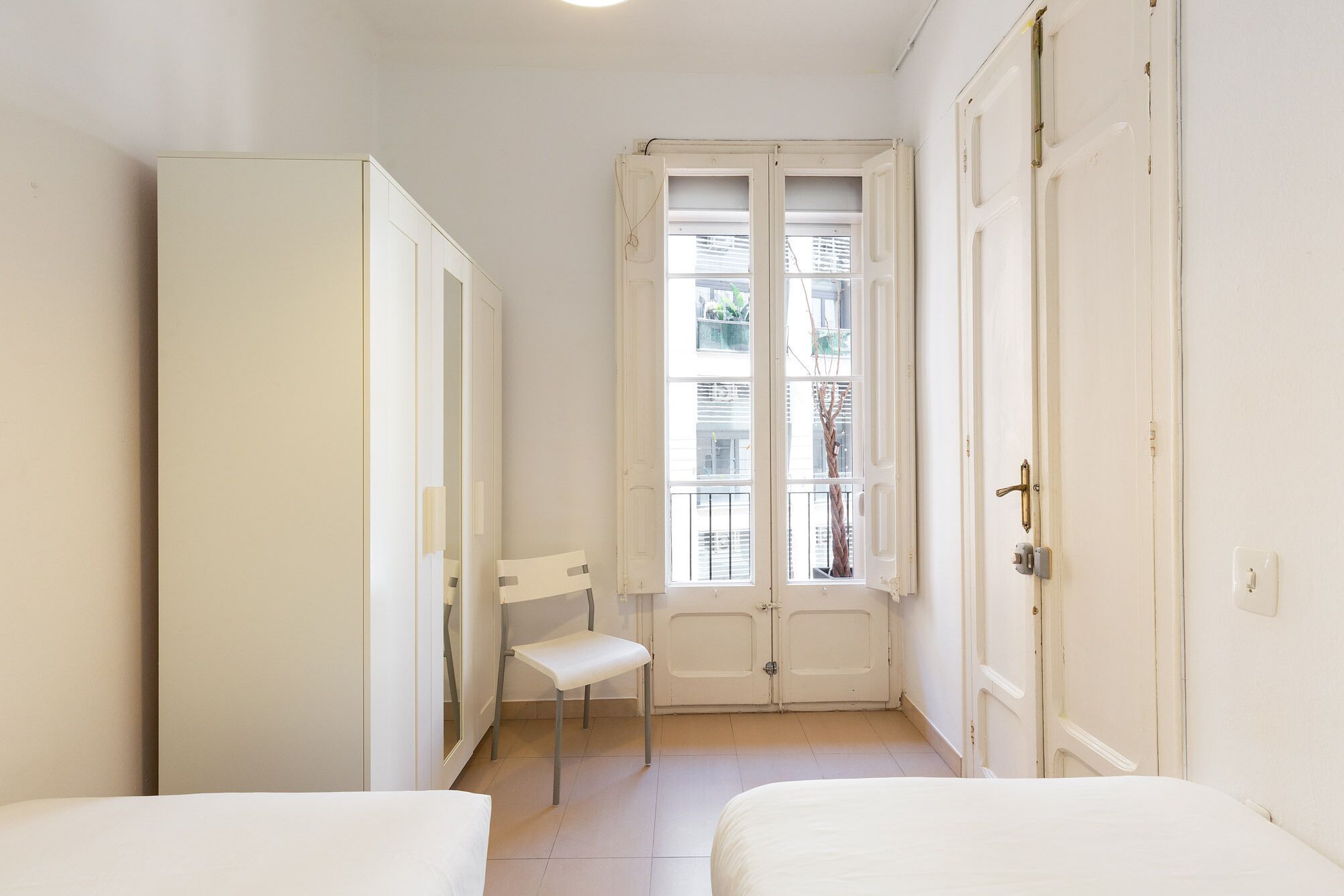 Una habitación pequeña con una cama individual, una silla y un armario.