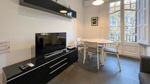 A modern kitchen with a black countertop, white chairs, and a dining table. - Stay Unique Apartments Cent (Barcelona)