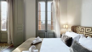 A hotel room with a bed, a bedside table with a lamp, a window with curtains, and a door. - Stay U-nique Apartments Borbó II (Barcelona)