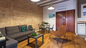 A modern living room with a brick wall, a sofa, a coffee table, and a dining area with chairs and a table.