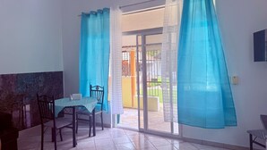 A room with a dining table and chairs, a sliding glass door leading to an outdoor area, and a TV mounted on the wall. - CasaLoca Cabarete (Cabarete)