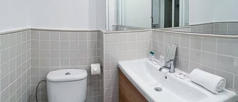 Un baño moderno con inodoro, lavabo y espejo.