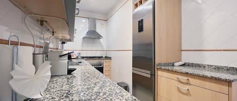 A modern kitchen with granite countertops, stainless steel appliances, and wooden cabinets.