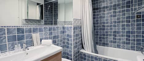 A modern bathroom with a large bathtub, a separate toilet, and a vanity with a mirror.