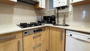 Una cuina moderna amb fogó de gas, cafetera i rentaplats.