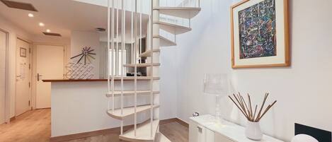 Un interior moderno con una escalera de caracol, una cocina minimalista y una obra de arte contemporánea en la pared.