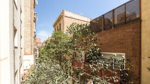 Une ruelle étroite bordée d’un bâtiment en briques, d’une clôture en métal et d’un arbre aux feuilles vertes.