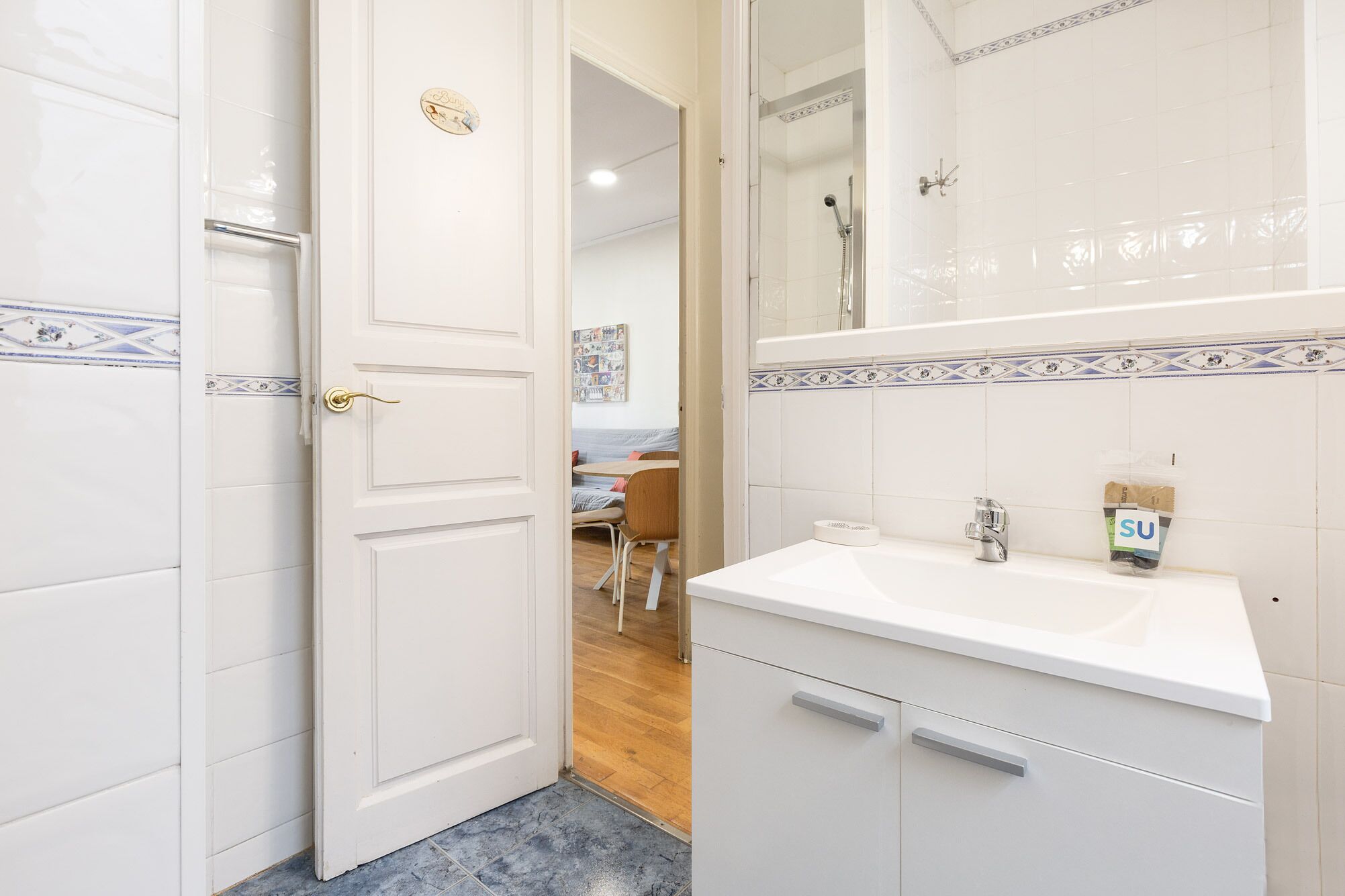 Un baño con azulejos blancos, un lavabo y una ducha.
