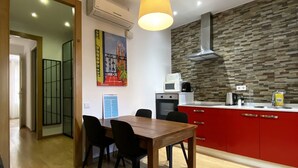 A modern kitchen with a wooden dining table, red cabinets, and a stone backsplash.
