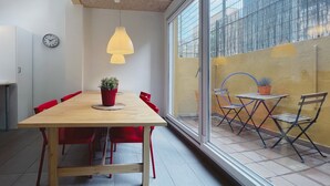 A modern dining area with a wooden table, red chairs, a clock, and a large window with a view of the outside. - Stay U-nique Apartment Maurici Serrahima (Barcelona)