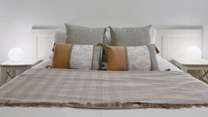 A neatly made bed with a patterned blanket, two pillows with leaf designs, and two bedside lamps. - Stay U-nique Apartment Maurici Serrahima (Barcelona)