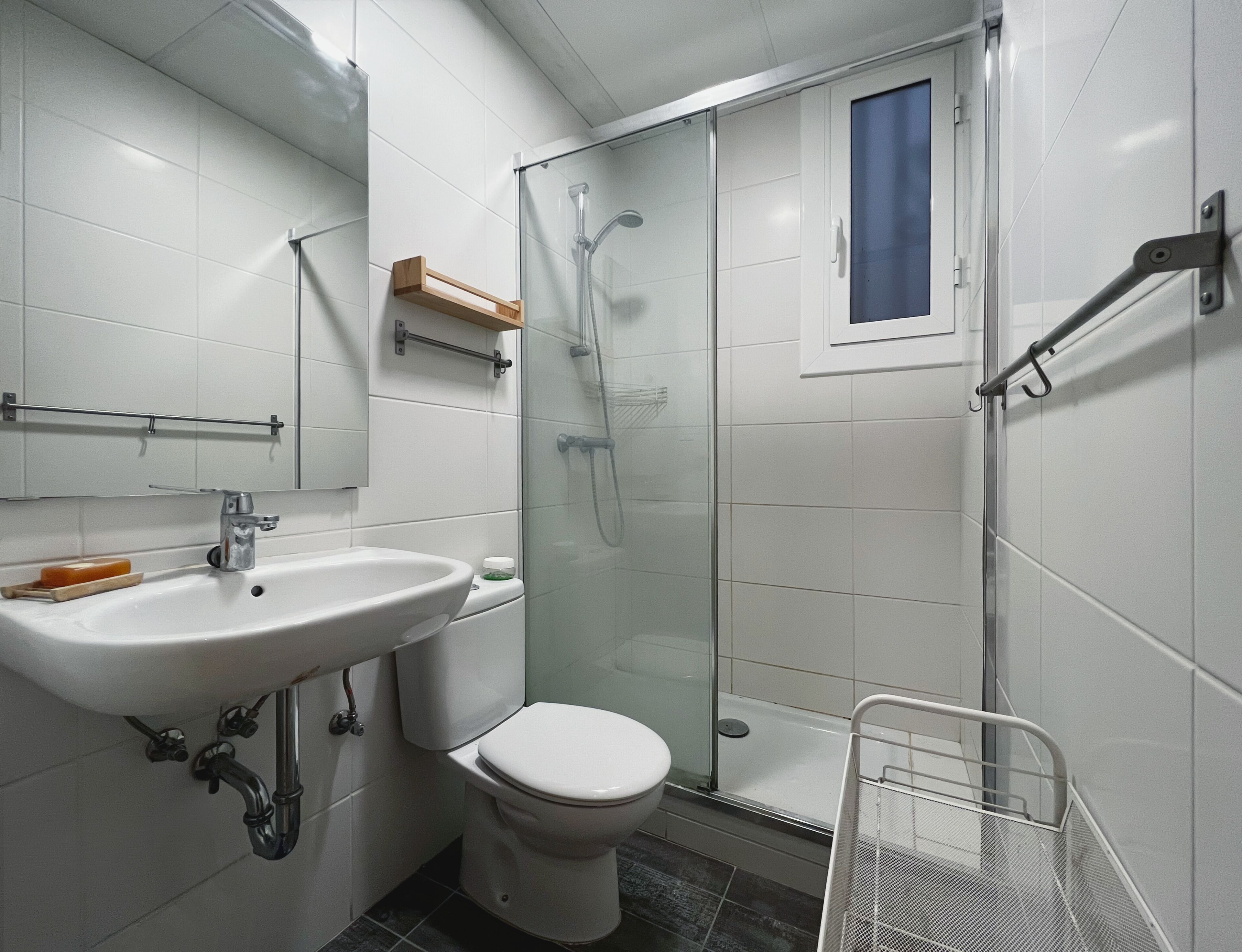 Ein modernes Badezimmer mit Duschkabine aus Glas, einem weißen Waschbecken und einer Toilette.