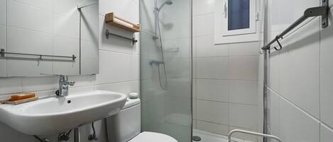 Ein modernes Badezimmer mit Duschkabine aus Glas, einem weißen Waschbecken und einer Toilette.