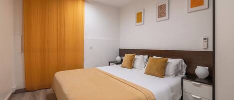 A hotel room with a bed, nightstand, and wall-mounted artwork.
