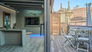 Eine Holzterrasse mit Sitzgelegenheiten und Blick auf eine Stadtansicht.