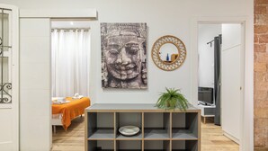 A room with a wooden console table, a Buddha statue, and a mirror on the wall. - Stay U-nique Apartments Caminal (Barcelona)