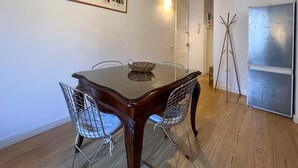 A dining area with a wooden table and wire mesh chairs, a framed photograph on the wall, and a refrigerator. - Stay U-nique Apartment Arago II (Barcelona)