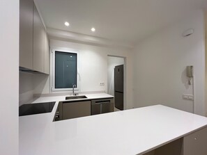 A modern kitchen with white cabinetry, a built-in dishwasher, and a refrigerator.