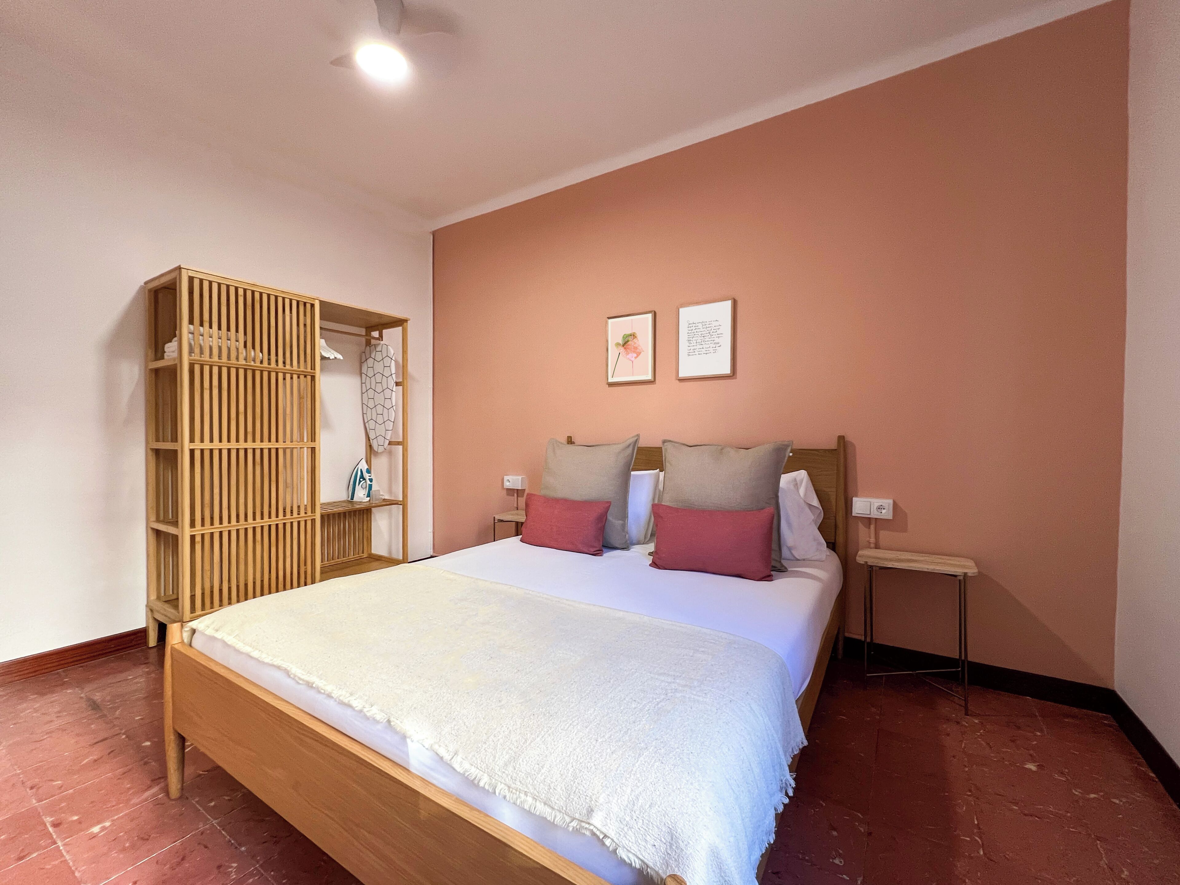 Un dormitorio con una cama de madera, un armario y dos cuadros en la pared.