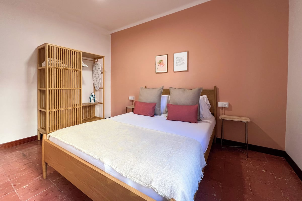 Une chambre à coucher avec un lit en bois, une armoire et deux tableaux encadrés accrochés au mur.