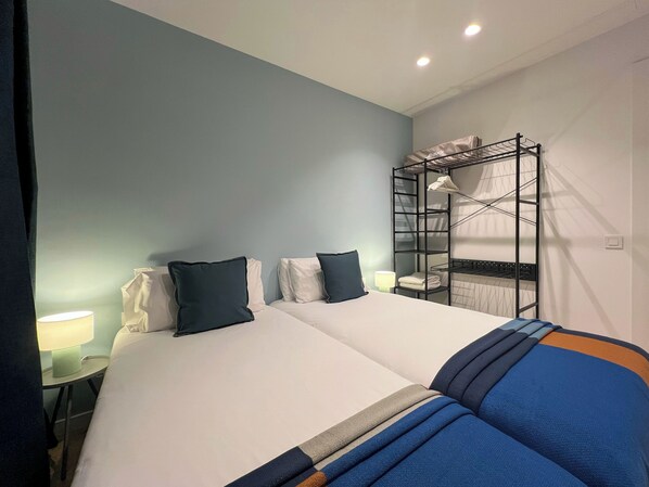 Ein Hotelzimmer mit einem Etagenbett, einem Nachttisch mit Lampe und einem Bett mit Kissen.