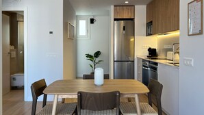 A modern kitchen with a wooden dining table, four chairs, a stainless steel refrigerator, and a coffee machine. - Stay U-nique Apartment Corsega II (Barcelona)