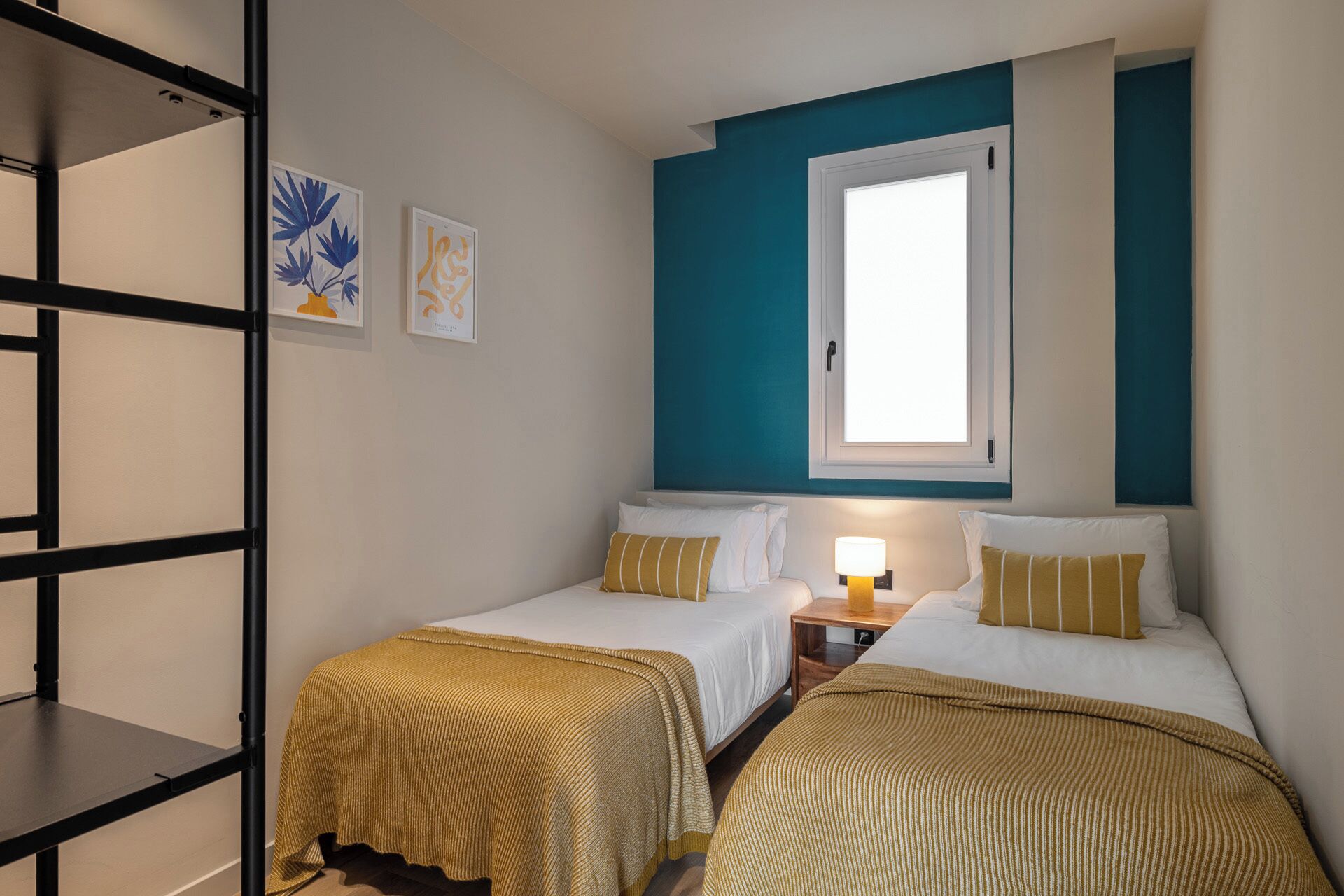 Une chambre avec deux lits simples, une fenêtre et une étagère.