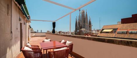 A rooftop terrace with a table and chairs, offering a view of a historic building.
