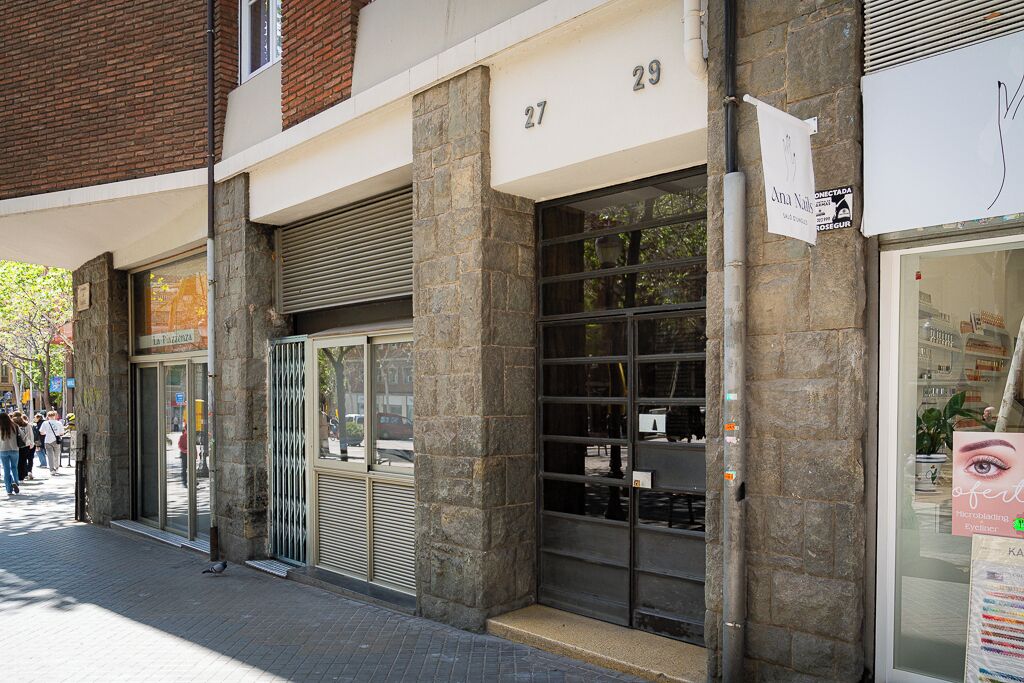 Un immeuble à la façade en pierre, portant les numéros 27 et 29, avec une entrée dotée d’une porte vitrée et une devanture visible avec une enseigne.
