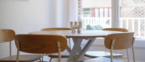 Una mesa redonda de madera con seis sillas, una vela y un cuadro en la pared.