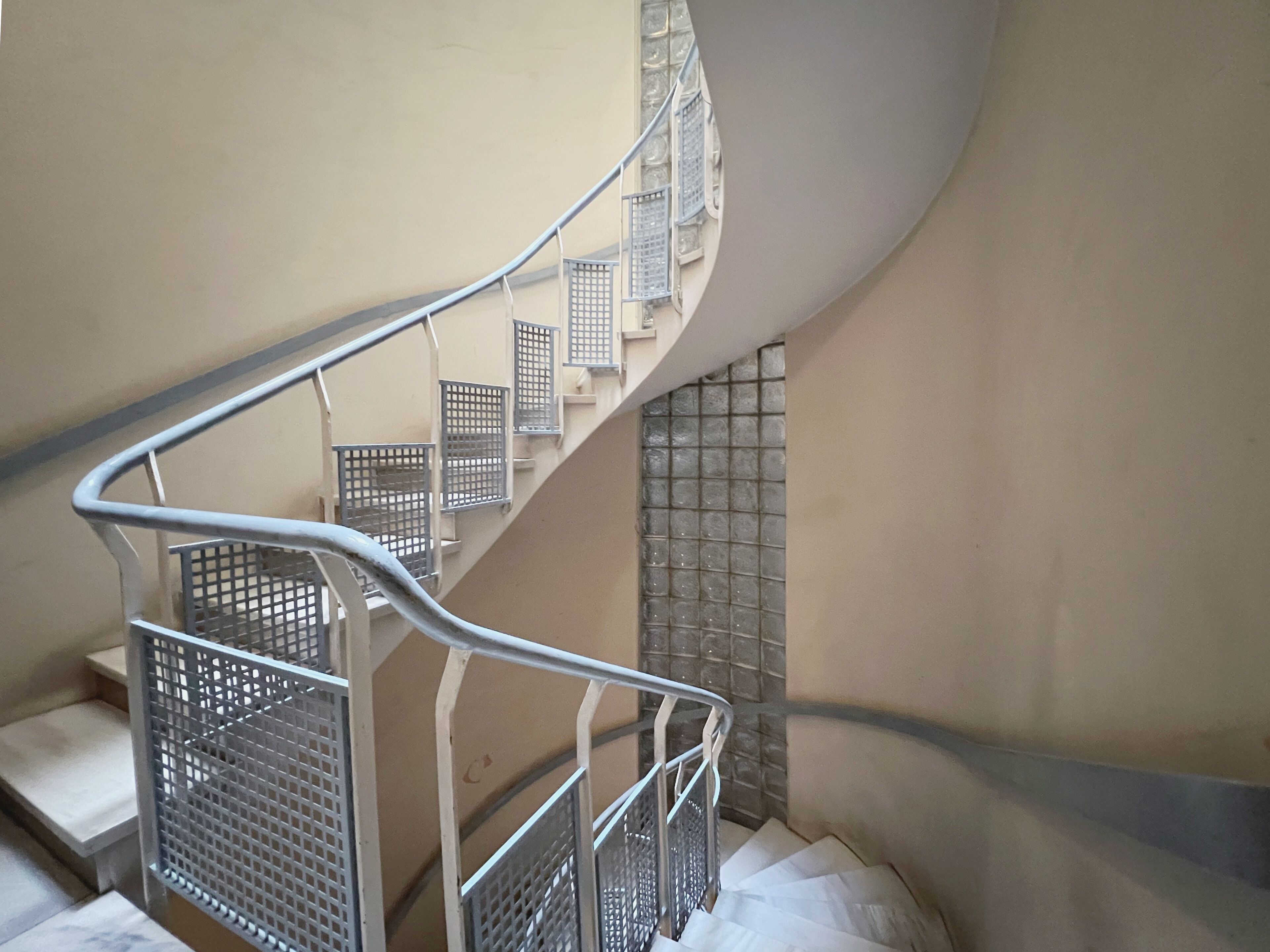 A spiral staircase with metal railings and a tiled wall.