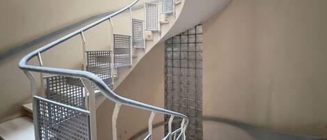 A spiral staircase with metal railings and a tiled wall.