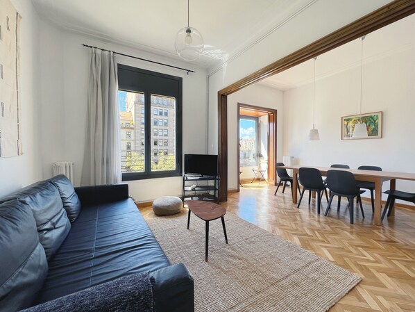 A modern living room with a sofa, a coffee table, and a dining area with chairs and a table. - Stay U-nique Apartment Passeig de Gràcia III (Barcelona)