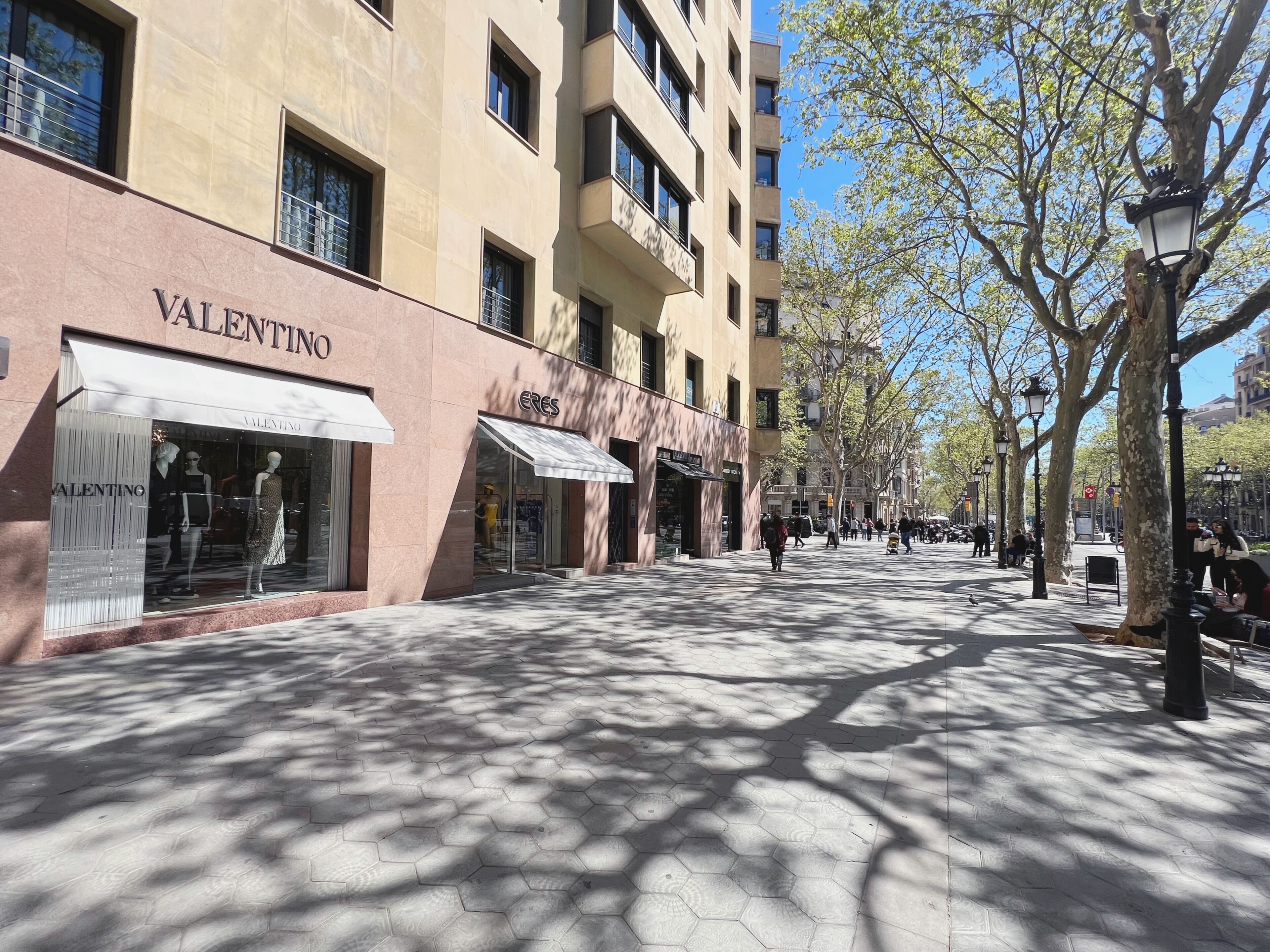A pedestrian street lined with shops, including a visible 'Valentino' store.