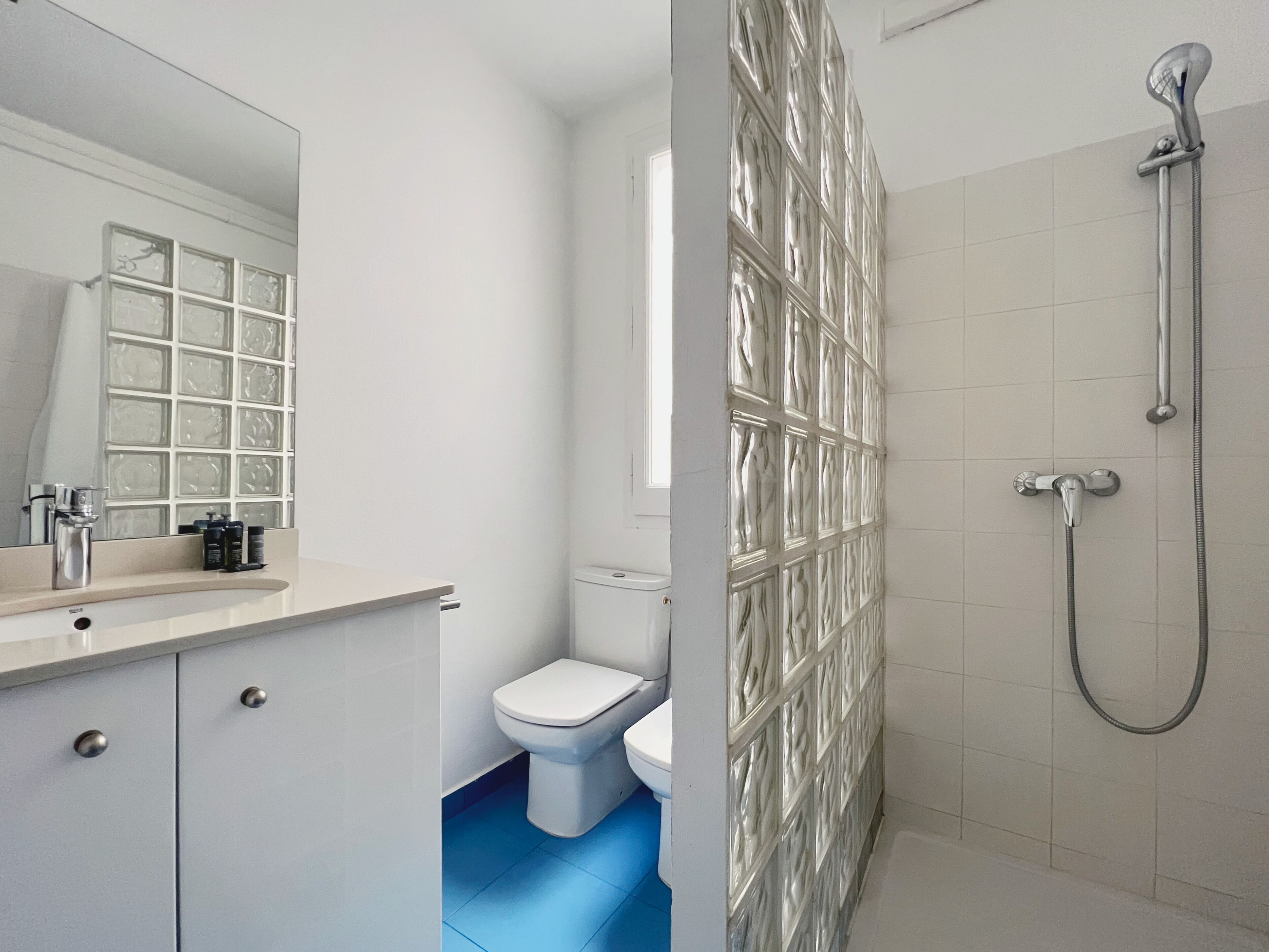Un baño moderno con un lavabo blanco, un inodoro y una zona de ducha.
